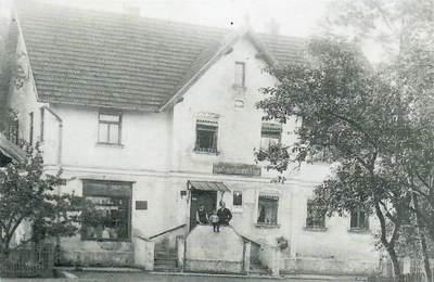 Das „Kaufhaus v. Heinrich Ammann" 1921 (heute Hauptstr. 5) V.re.: Heinrich Ammann mit Sohn Franz (später Ritterkreuzträger) und Ehefrau Anna. Ganz rechts an der Treppe unten der Postbriefkasten.