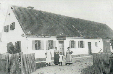 Von links der Bäckermeister Johann Steger mit Ehefrau Kreszenz und den Töchtern Kreszenz (verh. Förg) und Theresia. Auf dem Schild steht: „Bäckerei v. Johann Steger" Die Aufnahme entstand um 1912