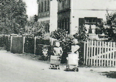 ..., während die Mädchen einen Puppenausflug veranstalten (um 1948). Hier Jutta und Bärbel Meyer (Vertriebene) vor dem Anwesen „Kropp". Die Hauptstraße konnte damals noch in den Spielbereich miteinbezogen werden.