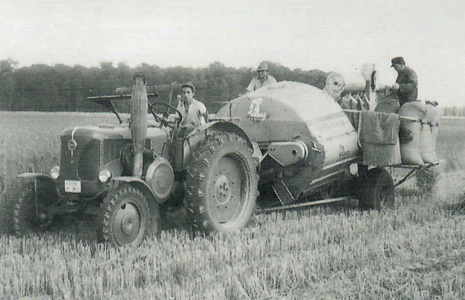 Mähdreschen beim Breitwanger 1959. Deutlich zu erkennen ist die Absackanlage. Die Ähren wurden seitlich aufgenommen. Auf dem Traktor der Lehrling A. Sandner, dahinter der Bauer Max Riegel, rechts Karl Klebl.