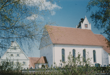 1955. Die Kirche ist neu geckt und getüncht. Das Turmdach ist noch alt. Das Zifferblatt ist quadratisch. Links der alte Pfarrhof und Pfarrstadel.